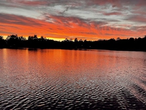 Ruhige Wasserfläche, die einen Sonnenuntergang im Himmel spiegelt.