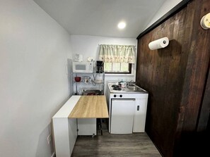 A compact kitchen with a wooden countertop, a white stove, and a microwave. - Cozy Waterfront Cottage Rental on the Shores of Harvey Lake in Northwood, New Hampshire (Northwood)
