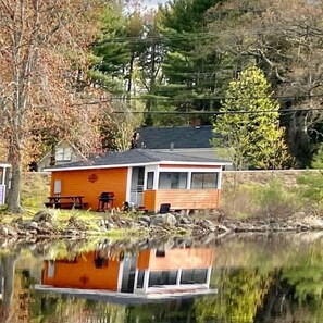 Eine Holzhütte mit Steg, umgeben von Bäumen und einem See.