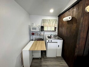 Eine kleine Küche mit einer Holzausziehtheke, einem weißen Herd und einer Mikrowelle.