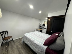 Ein Schlafzimmer mit einem Bett, einem Sessel, einem Schreibtisch und einer Tür.