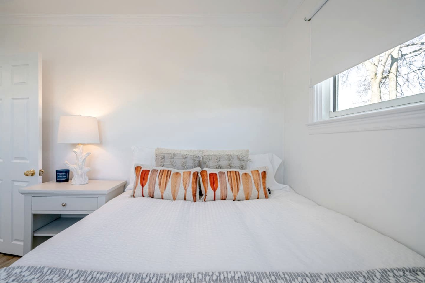 Une chambre à coucher avec un lit, une table de chevet, une lampe et une fenêtre.