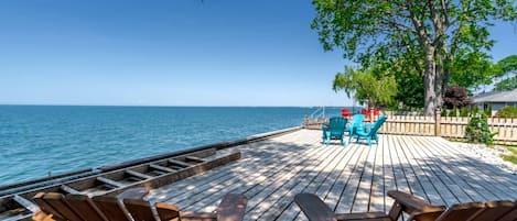 A wooden deck with chairs and a view of the sea.