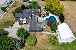 Vue aérienne d’une propriété résidentielle comprenant une piscine, plusieurs maisons et une cour clôturée.
