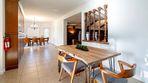 A dining area with a wooden table and chairs, a fire extinguisher, and a kitchen in the background. - Relaxing Luxury Stay with Spa Bath, Pool Loungers & Outdoor Fire Pit in Ontario, Canada (Kingsville)