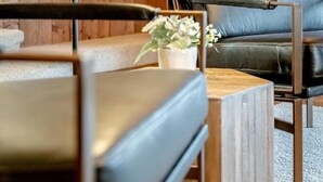 A room with wooden panel walls, a black leather sofa, a wooden coffee table, and a wall-mounted light fixture. - Relaxing Luxury Stay with Spa Bath, Pool Loungers & Outdoor Fire Pit in Ontario, Canada (Kingsville)