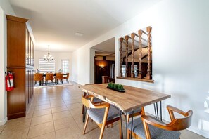 Un coin repas avec une table et des chaises en bois, un extincteur et une cuisine en arrière-plan.