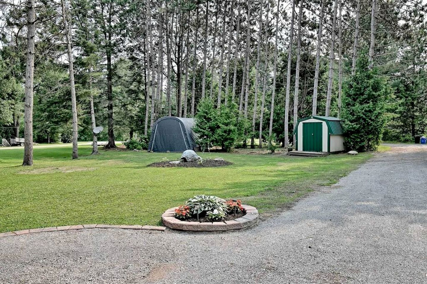A campground with a tent, a small shed, and a paved path.
