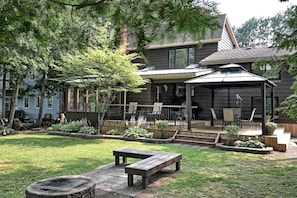 Une maison moderne dotée d’un patio couvert, d’un foyer extérieur et d’un jardin bien entretenu.