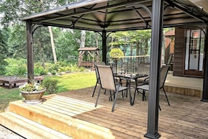 Une terrasse extérieure couverte avec une plateforme en bois, une table et des chaises, et un pot de fleurs.