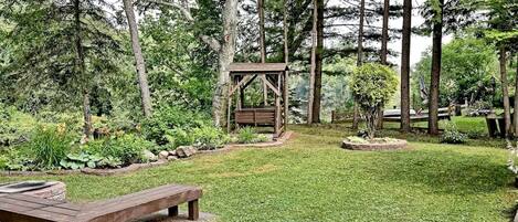 Un quiosco de madera en un jardín con un banco y un pequeño estanque.