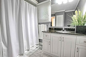 Une salle de bain avec un rideau de douche, un lavabo et un miroir.