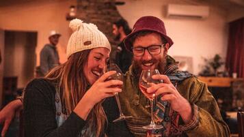 Two people sitting at a table with wine glasses, in a warmly lit indoor setting.