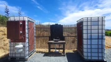 A portable restroom setup with a metal frame, a wooden bench, and a sink.
