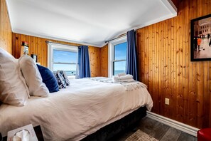 Une chambre avec un grand lit, des murs en bois et une vue sur la mer.