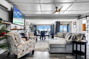 A spacious living area with a ceiling fan, a large TV, and a view of the ocean. - Charming Cottage on Lake Erie for an Unforgettable Kingsville Getaway in Ontario (Kingsville)
