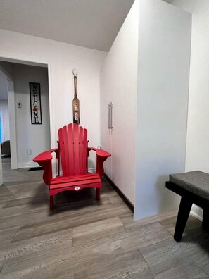 Una silla Adirondack roja en un pasillo con un cartel que dice 'Welcome' y un cartel que dice 'Lake House' en la pared.