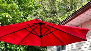 A patio with a table and chairs, an umbrella, and a white house in the background.