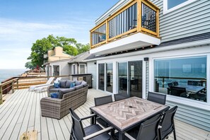 A deck with a sofa, table, and chairs, overlooking the sea. - Coast Rental with Hot-Tub and Equipped Deck in Ontario (Leamington)