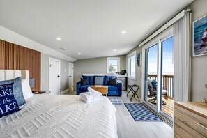 A modern bedroom with a large bed, a sofa, a small kitchen, and a balcony with a view. - Coast Rental with Hot-Tub and Equipped Deck in Ontario (Leamington)