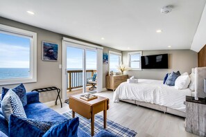A bedroom with a bed, a TV, a dresser, and a balcony with a view of the ocean. - Coast Rental with Hot-Tub and Equipped Deck in Ontario (Leamington)