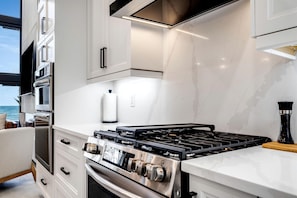 Une cuisine moderne équipée d’une cuisinière à gaz, d’un four et d’un micro-ondes encastré.