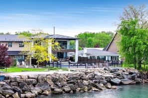 Ein Anwesen am Seeufer mit einem modernen Haus, Sitzgelegenheiten im Freien und einem Steg.