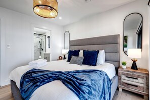 A modern bedroom with a large bed, bedside tables, a mirror, and a hanging light fixture. - Sophisticated Shoreline Retreat with Sunset Patio & Poolside Lounging in Ontario, Canada (Leamington)