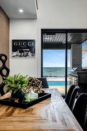 Ein Essbereich mit Meerblick, ein Gucci-Poster und ein Grill im Freien.