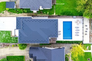 A residential property with a large swimming pool, multiple decks, and a well-maintained lawn. - Sophisticated Shoreline Retreat with Sunset Patio & Poolside Lounging in Ontario, Canada (Leamington)