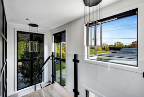 Un interior modern amb grans finestres, una escala i vista a un pàrquing.