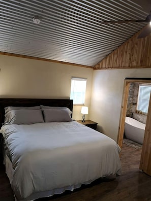 Una camera da letto con un letto, un comodino, una finestra e un bagno con una vasca.
