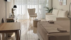 Quarto de hotel moderno com cama, sofá, mesa de jantar e televisão.