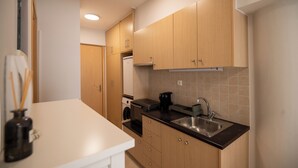 Uma cozinha moderna com armários de madeira, uma pia de aço inoxidável e bancada branca.