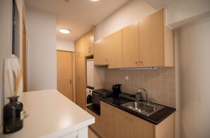 A modern kitchen with wooden cabinets, a stainless steel sink, and a white countertop. - ATOM – Minimal Luxury Stay in Rethymno with Parking & Self Check-in (Rethymno)