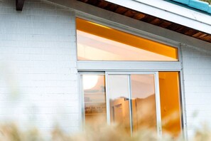 A white building with a large window and a door. - Magical Queenstown Cabin with Lake Views (Queenstown)
