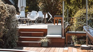 Une terrasse en bois aménagée avec du mobilier d’extérieur, notamment des chaises et une table.