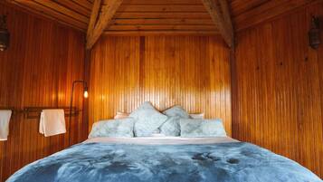 A wooden-paneled room with a bed, a wall-mounted light fixture, and a towel rack.