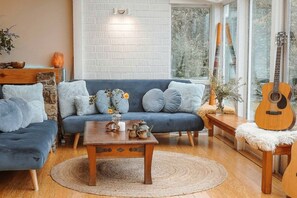 Una sala de estar acogedora con un sofá azul, una mesa de centro de madera y una guitarra.