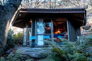 A rustic cabin with a bed, a bench, and a dining table.