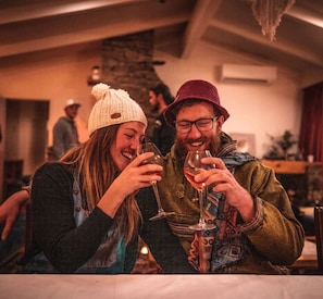 Two people sitting at a table with wine glasses, in a warmly lit indoor setting. - Charming Accommodation in Queenstown with Lake Wakatipu Views (Queenstown)