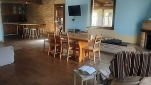 Ein geräumiger Wohnbereich mit Esstisch aus Holz, Barhocker, einer Couch und einem Kamin.