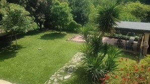 Ein üppiger Garten mit Rasen, Bäumen und einer Terrasse mit Gartenmöbeln.