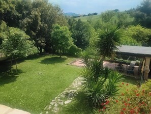 Ein üppiger Garten mit Rasen, Bäumen und einer Terrasse mit Gartenmöbeln.