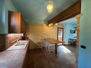 Eine Küche mit Holztisch, Barhocker, Spüle und einer Steinwand.