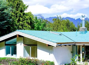 A modern house with a sloped roof, large windows, and a chimney.