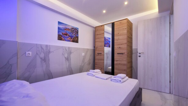 Un dormitorio moderno con una cama grande, un armario de madera y un espejo montado en la pared.