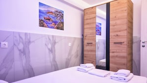 Un dormitorio con cama, un armario de madera, una pared de mármol y un cuadro.
