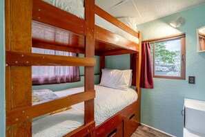 A bunk bed room with a window, a small desk, and a wall-mounted light fixture.