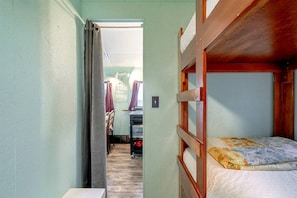 Une chambre avec un lit superposé, une tête de lit en bois, une petite table et une chaise.